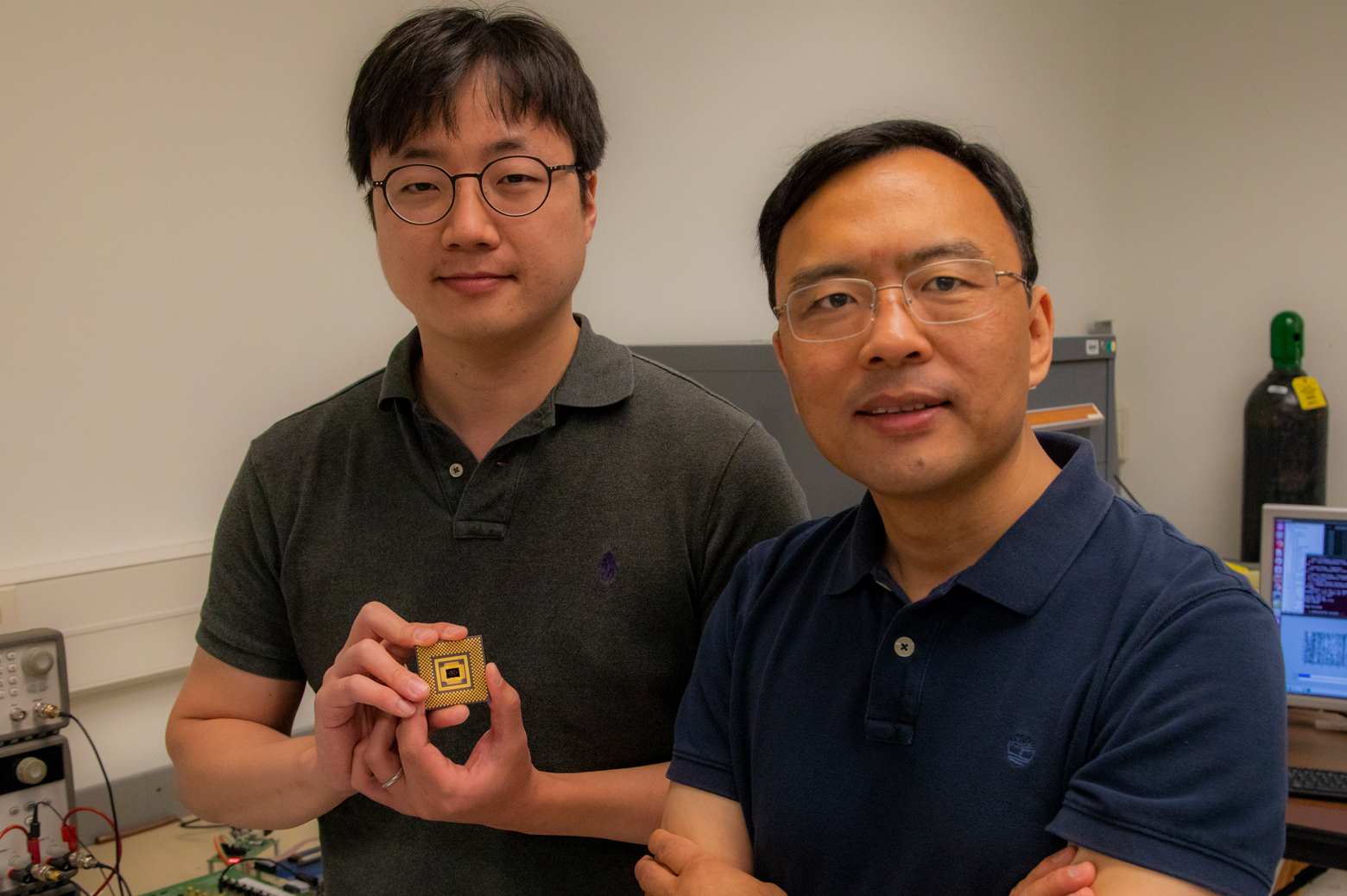 Wei Lu stands with first author Seung Hwan Lee, an electrical engineering PhD student, who holds the memristor array. Photo: Robert Coelius, Michigan Engineering Communications & Marketing