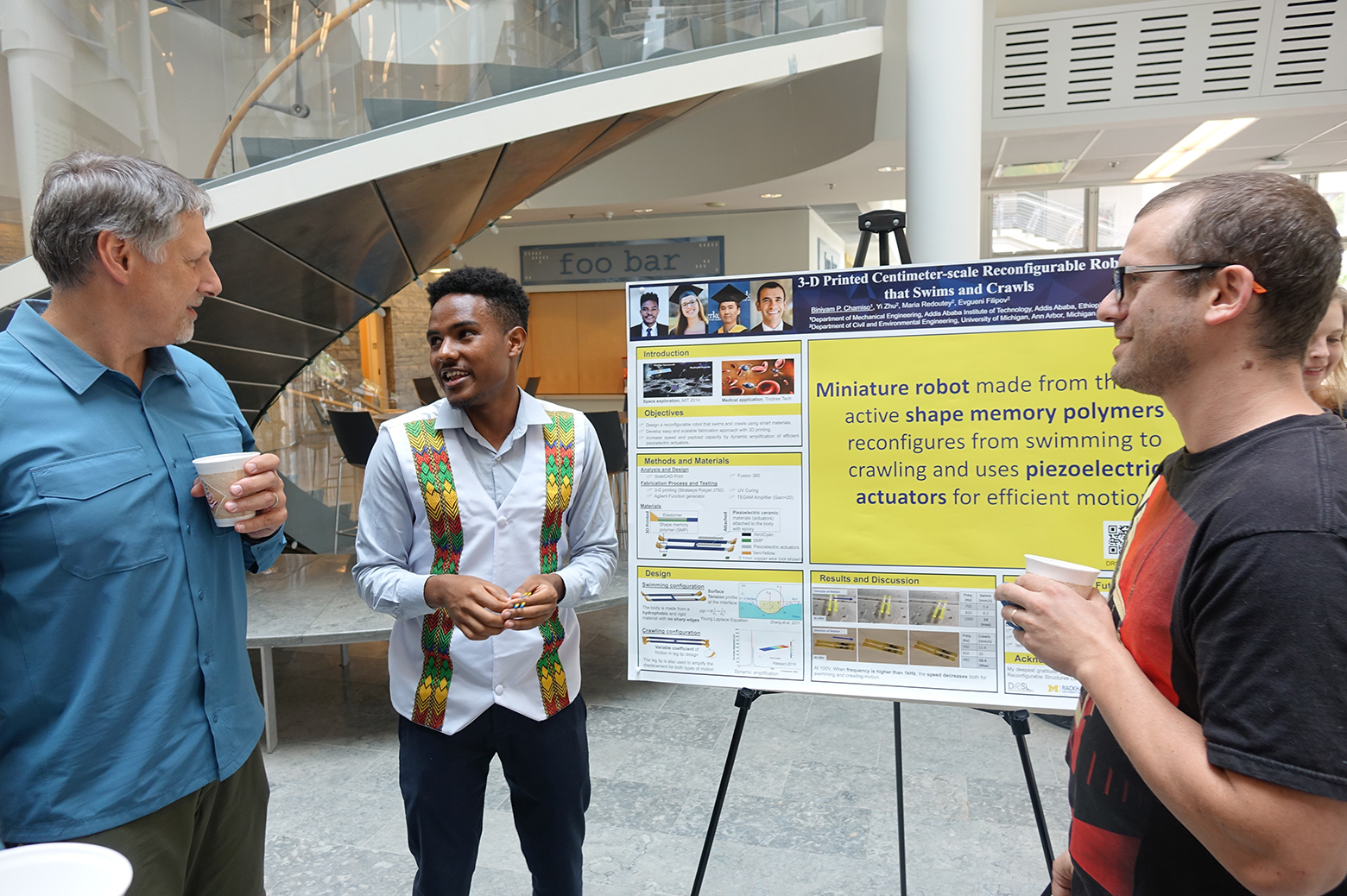 Astudent shows a poster to two faculty