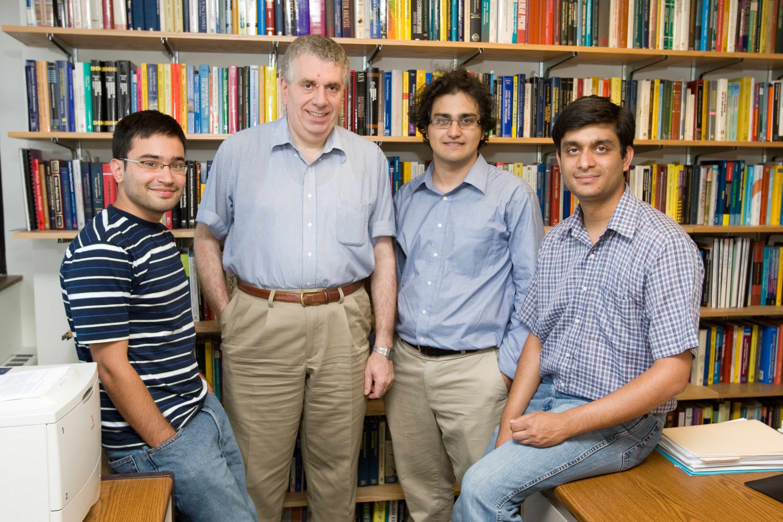Teneketzis stands with a few of his PhD students.