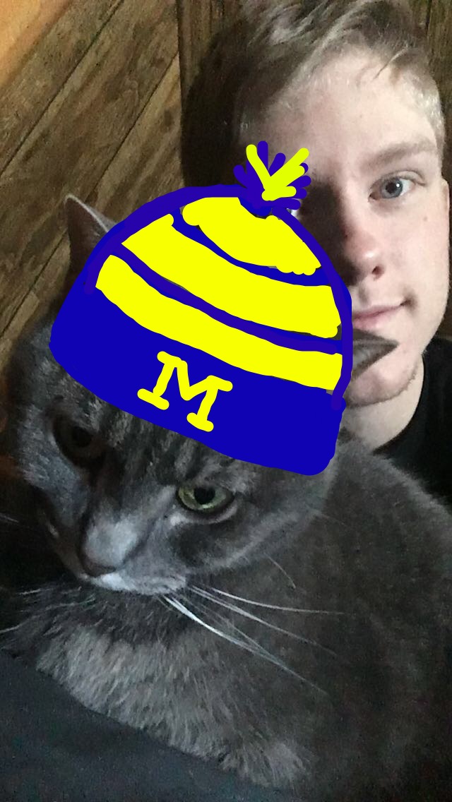 Jeremy and his cat with a digital illustration of a Michigan hat on the cat