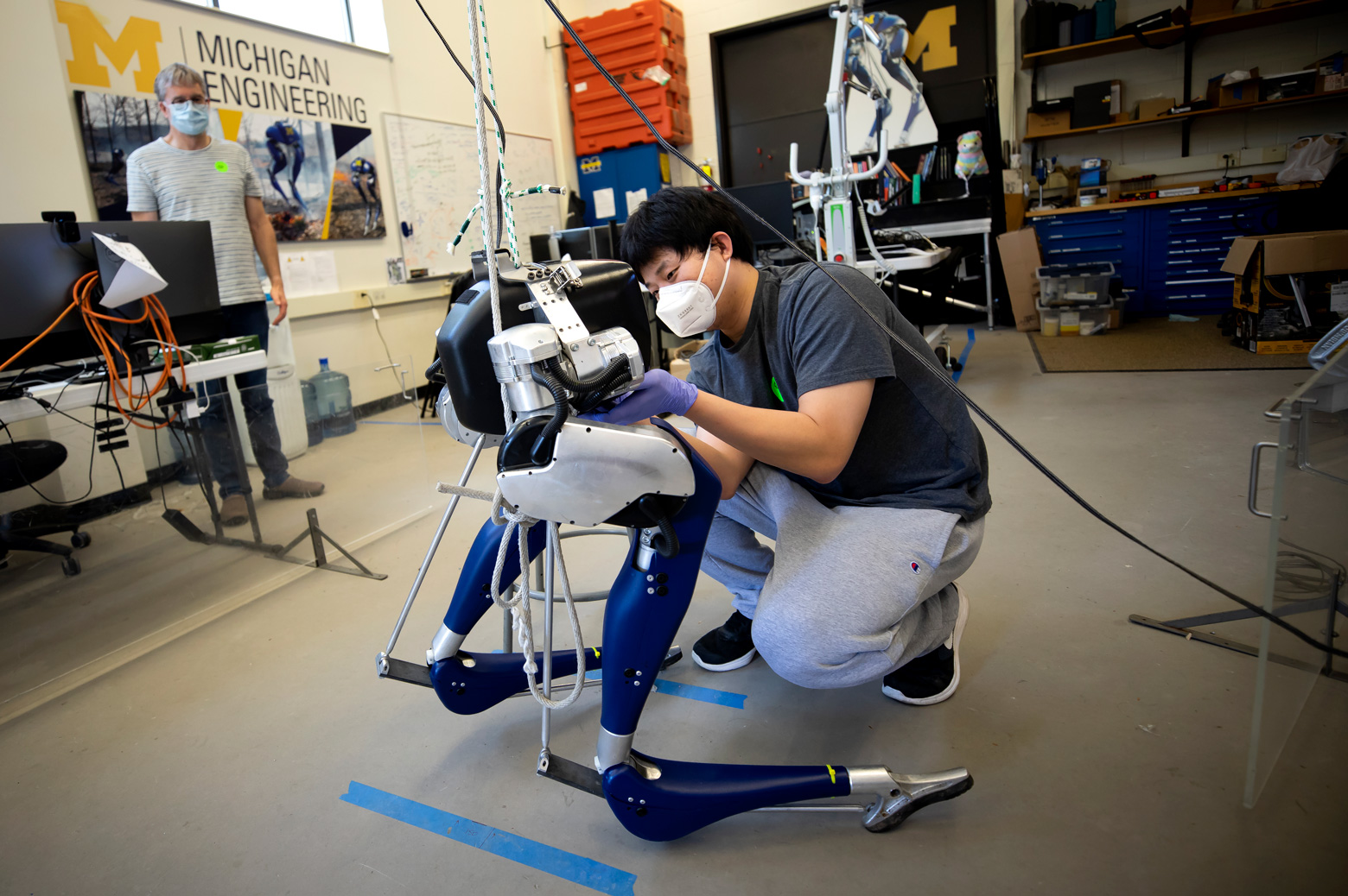 Yukai Gong, Robotics PhD Student, installs a battery into Cassie, a bipedal robot, as Jessy Grizzle, Director of the Robotics Institute, looks on in their lab on North Campus of the University of Michigan in Ann Arbor, MI on May 26, 2020.