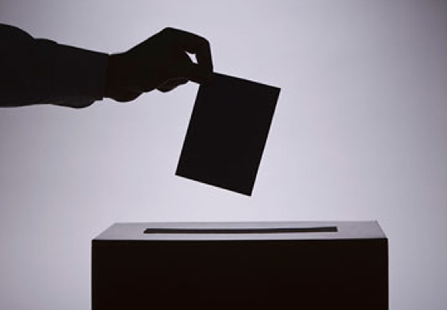 A hand placing a ballot in a ballot box