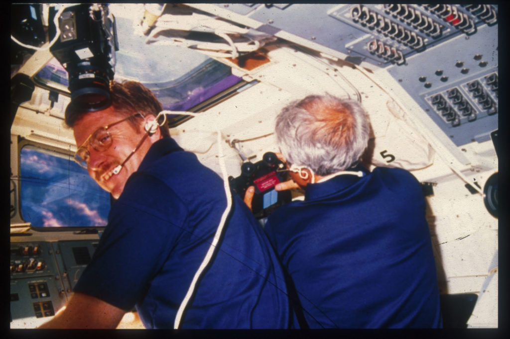England and Bartoe inside the space shuttle challenger during orbit with view of space out the window