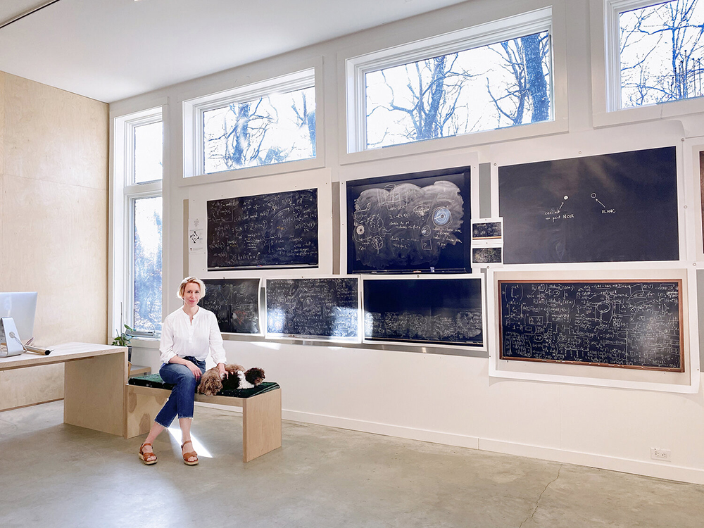photo of Wynne in her studio in front of 7 blackboards
