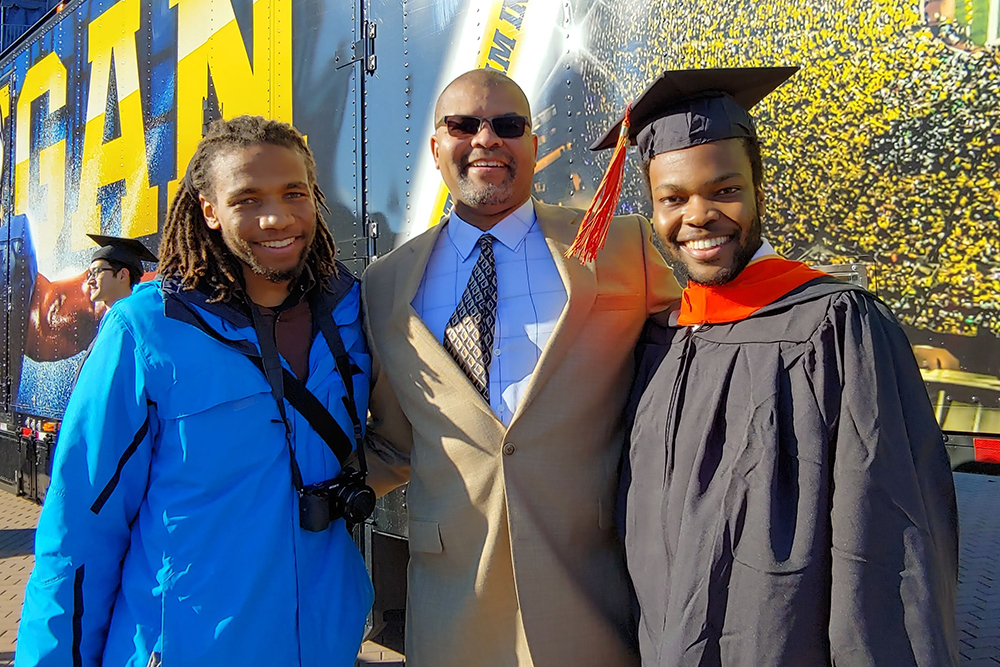 Rutledge and his two sons in front of a Michigan billboard for Lee's graduation. 