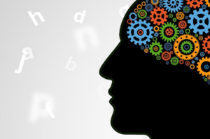 Silhouette of a person's face with colored gears in their head. Blurred letters in the background.