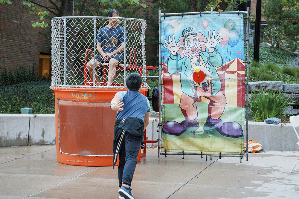 A ball sails toward the dunk button as Prof. Giebink looks on and a child completes his follow-through