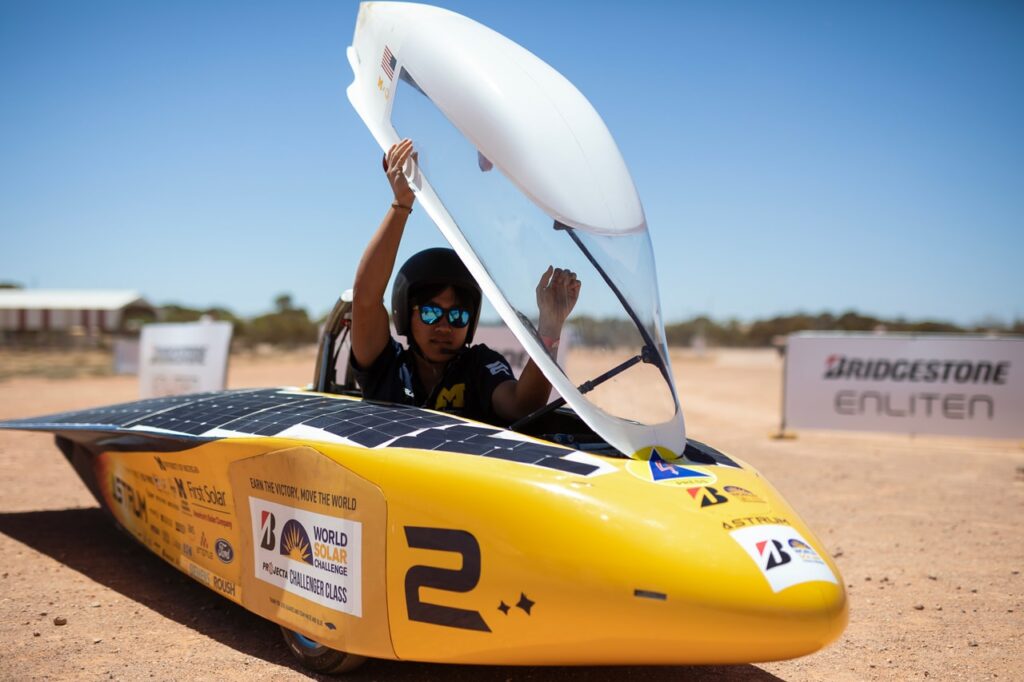 the driver opens the solar car hatch to exit the car