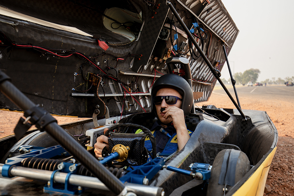 a student sits inside the solar car and tests the comms
