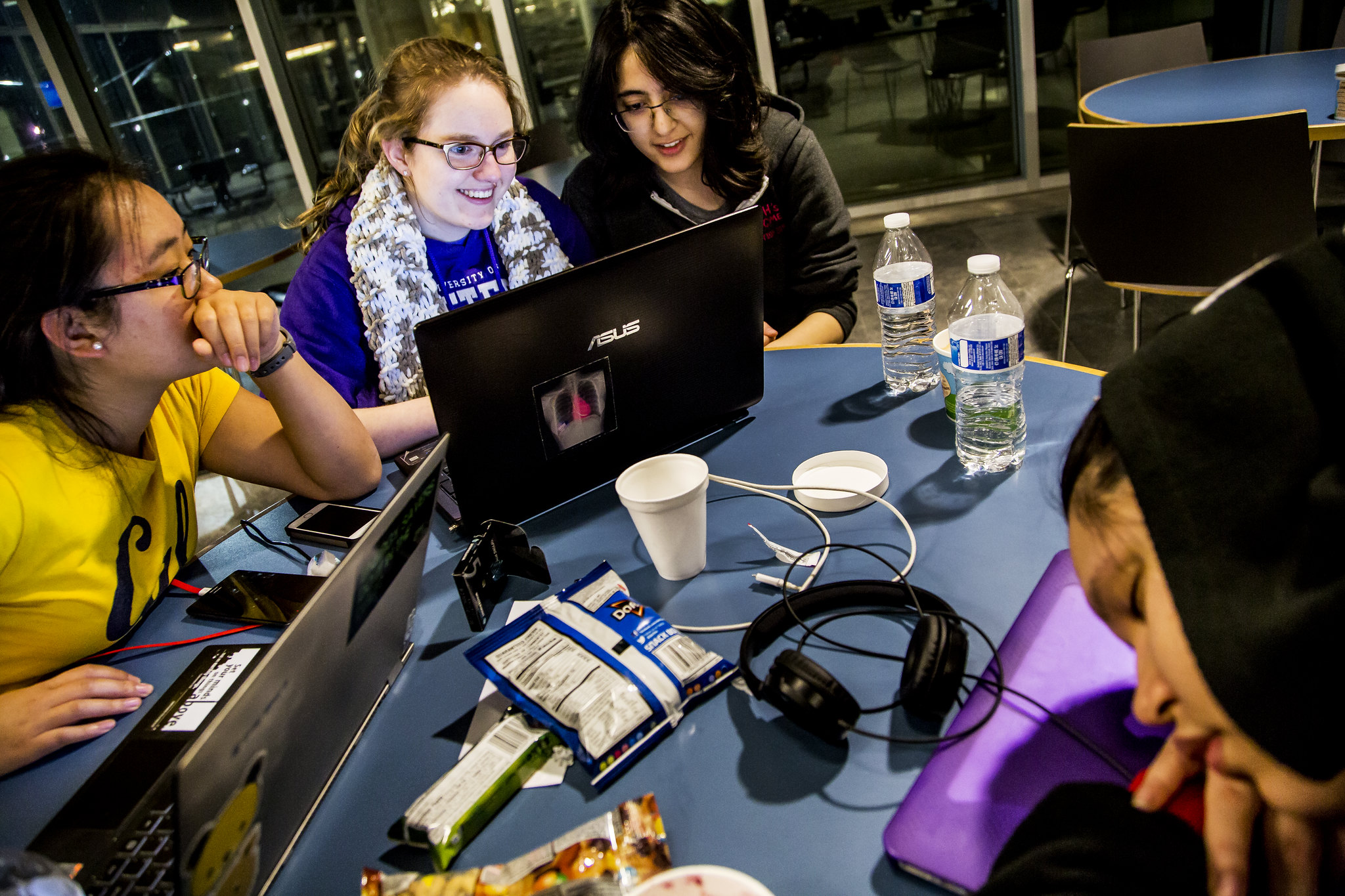 Three female students work on computers, smiling.