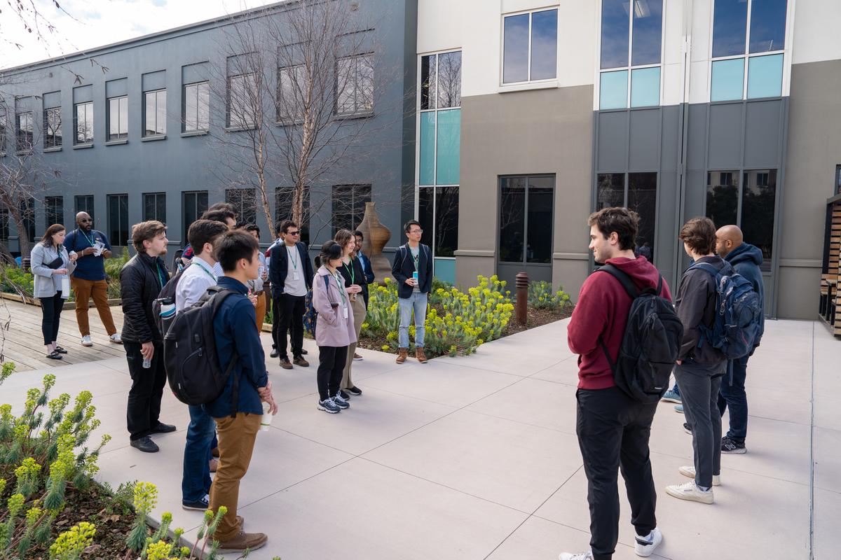 Students stand in a courtyard on the Meta campus, surrounded by flowered gardens.