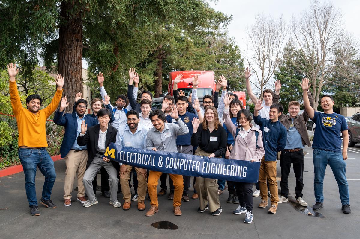 Students and engineers from Kodiak Robotics wave in front of an automated semi-truck with the University of Michigan Electrical & Computer Engineering banner.