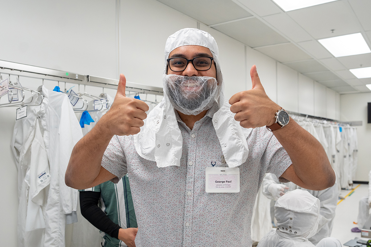 One student gives two thumbs up while wearing a hood and a beard cover before entering the KLA cleanroom.