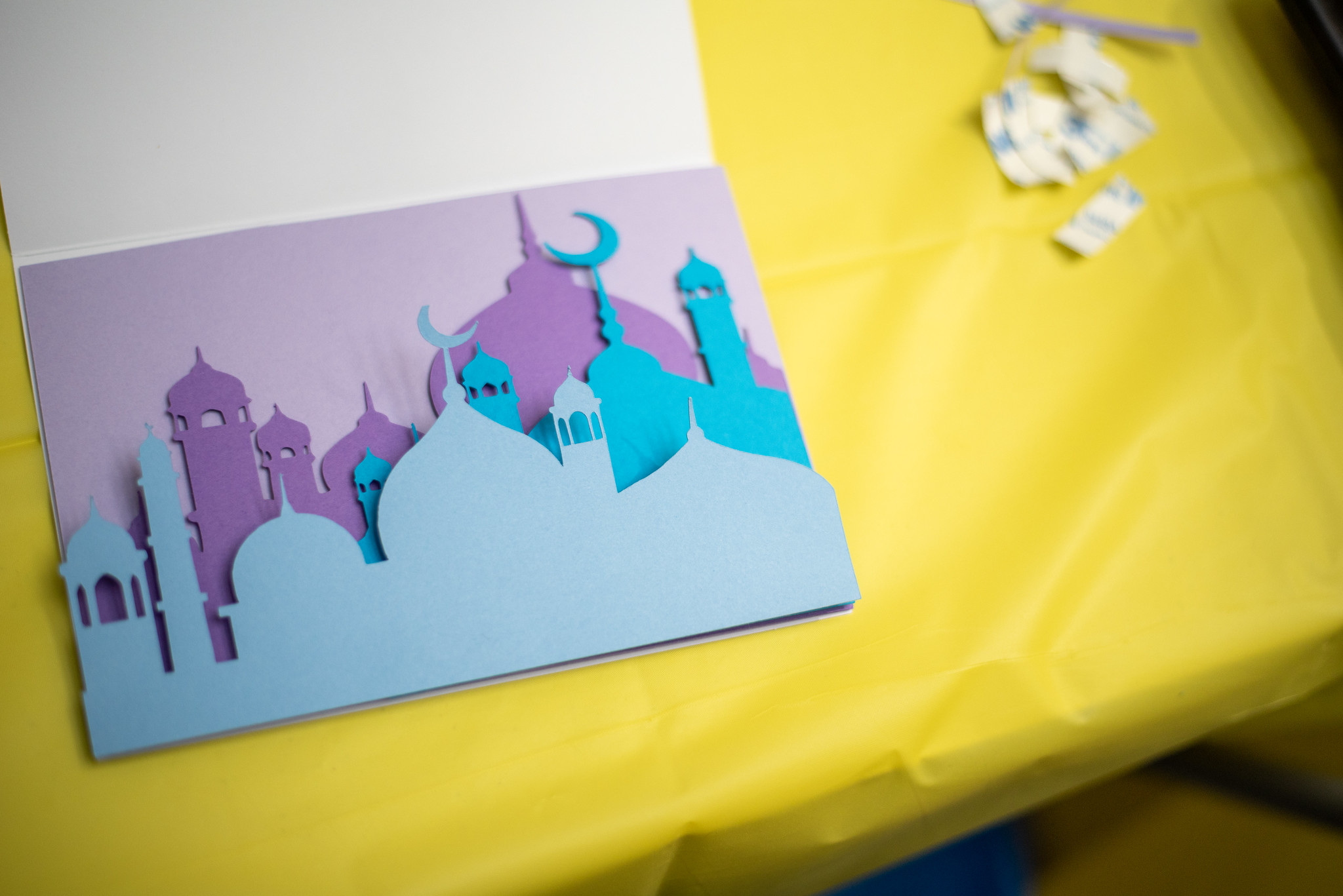 A closeup shot of one of the crafts. Overlapping paper cutouts in blue and purple are attached to white cardstock.