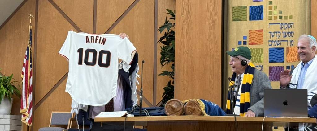 Bernie Arfin looks at the sports jersey showing his name and the number 100 at his birthday party.