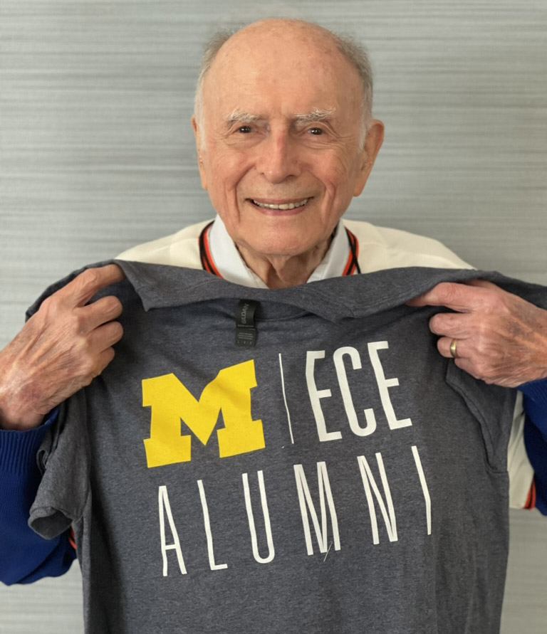 Bernie Arfin holds up a Michigan ECE Alumni tshirt.