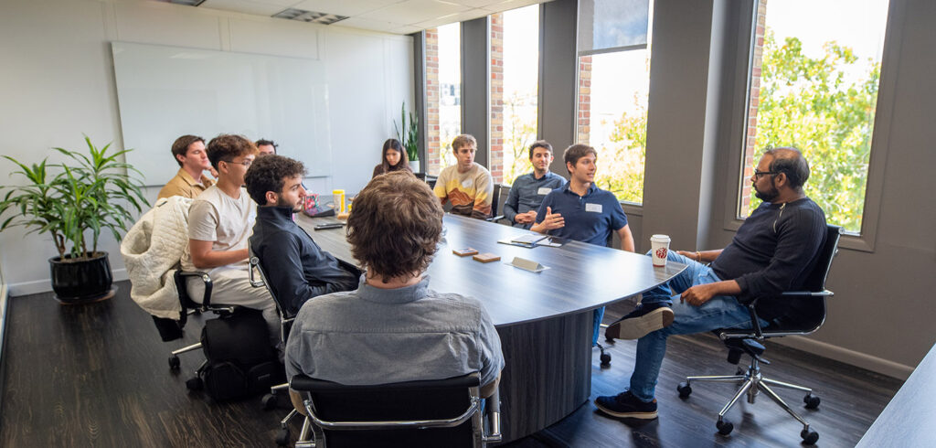 Students sitting around a table talking with the founder.