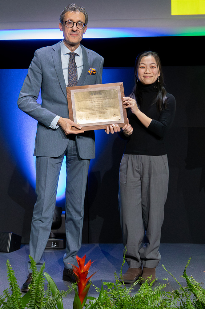 A tall man and a shorter woman stand side-by-side holding a shiny framed award plaque.