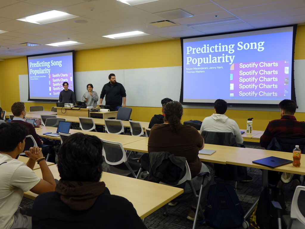 a group of three students presenting on a screen in front of a class.