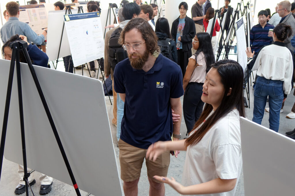 A faculty member listens as a student describes her poster project.