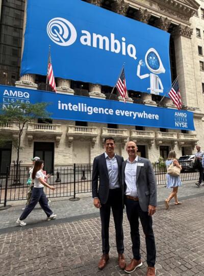 Scott Hanson and Dennis Sylvester standing outside the New York Stock Exchange with a large Ambiq sign in the background