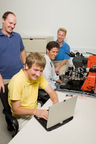 4 researchers working in a circuits lab, with a computer and testing equipment