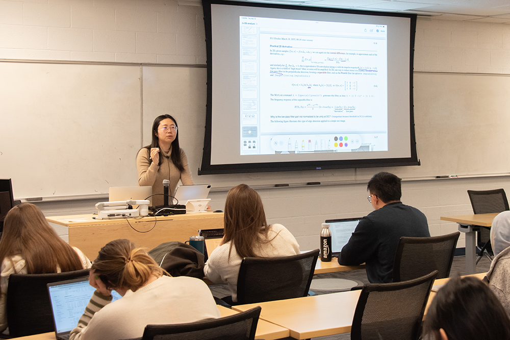 A woman stands at the front of the classroom giving a lecture.